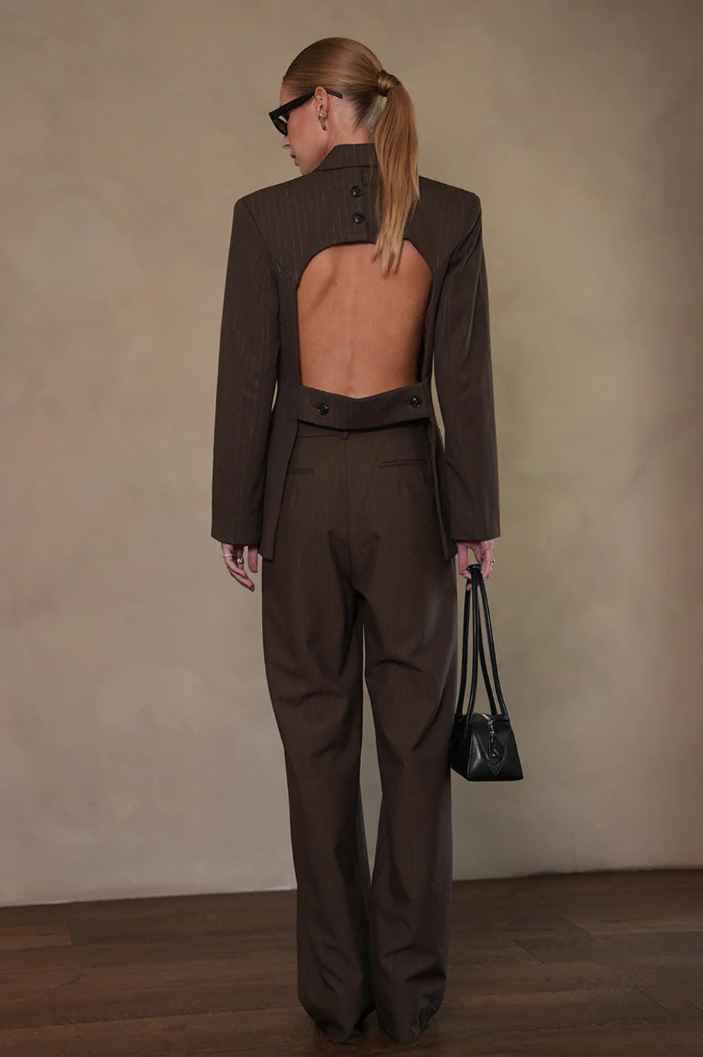 Woman wearing a brown suit with open back, tailored trousers